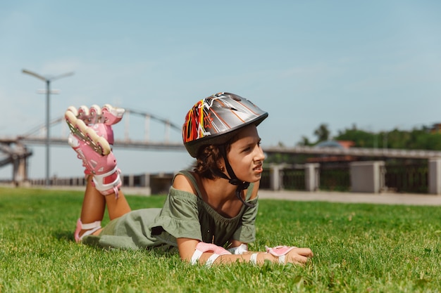 Teenage girl in a helmet learns to ride on roller skates outdoors