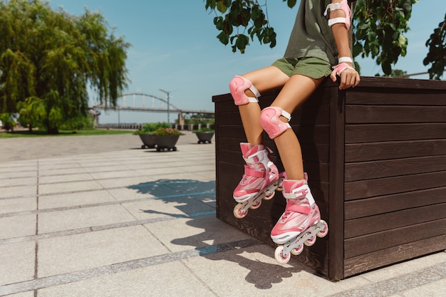 Free photo teenage girl in a helmet learns to ride on roller skates outdoors