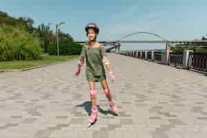 Free photo teenage girl in a helmet learns to ride on roller skates outdoors