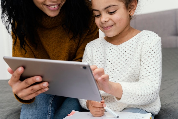 オンライン学校でタブレットを使用して妹を助ける10代の少女