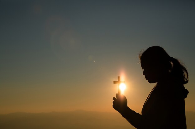 Девочка-подросток держит крест с молитвой. Мир, надежда, мечты концепции.