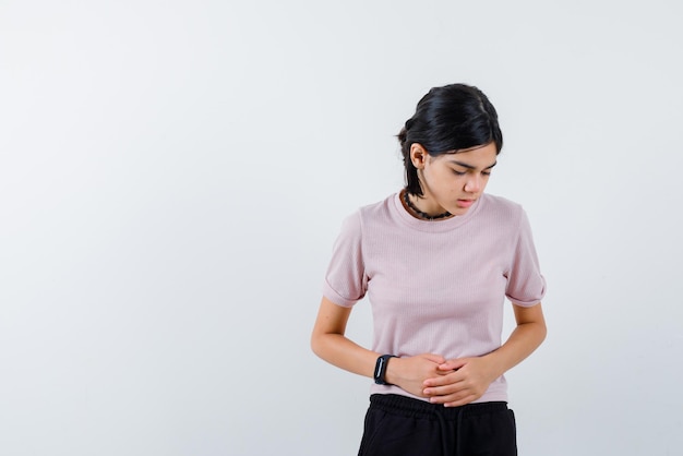 Teenage girl holding her stomach with hands on white background