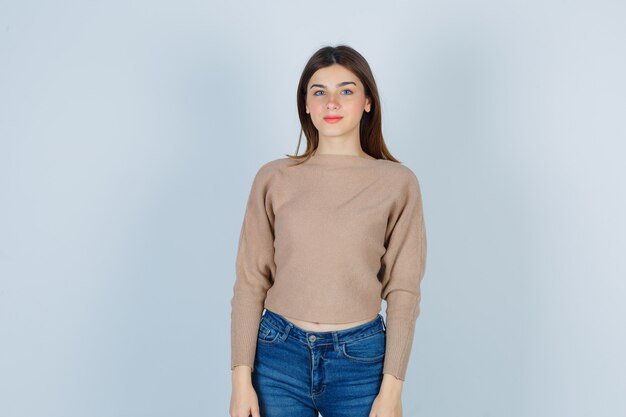 Девочка-подросток смотрит спереди в свитере, джинсах и выглядит разумно, вид спереди.