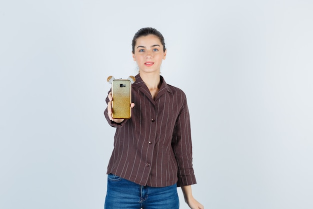 Adolescente che offre smartphone in camicia a righe marrone e sembra gentile. vista frontale. Foto Gratuite