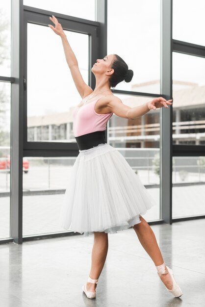 Девочка-подросток, практикующая балетный танец возле стеклянной стены