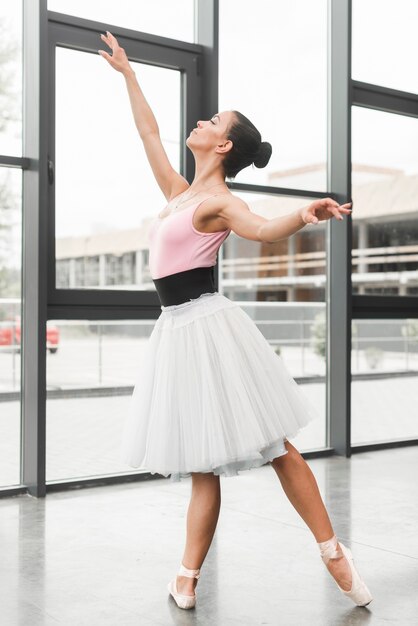 Teenage girl practicing ballet dance near glass wall