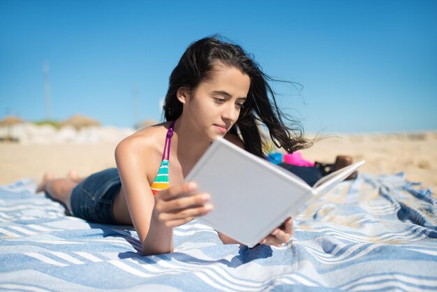 Teenage girl reading at beach