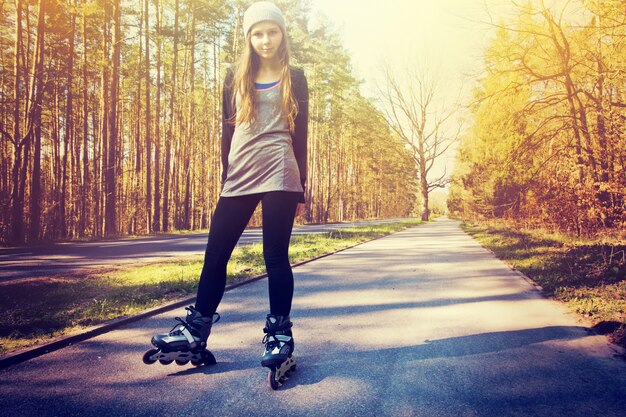 Девочка-подросток на роликовых коньках летом.