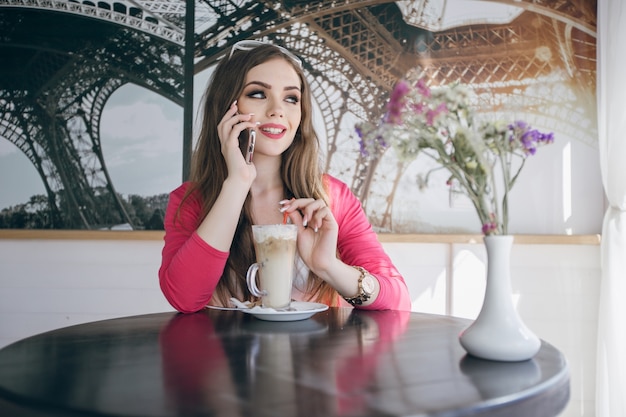 Teenage girl smiling while talking on the phone and having a chocolate milkshake