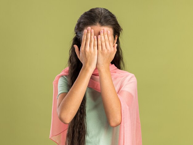복사 공간이 있는 올리브 녹색 벽에 격리된 손으로 얼굴을 덮고 있는 목도리를 입은 10대 소녀