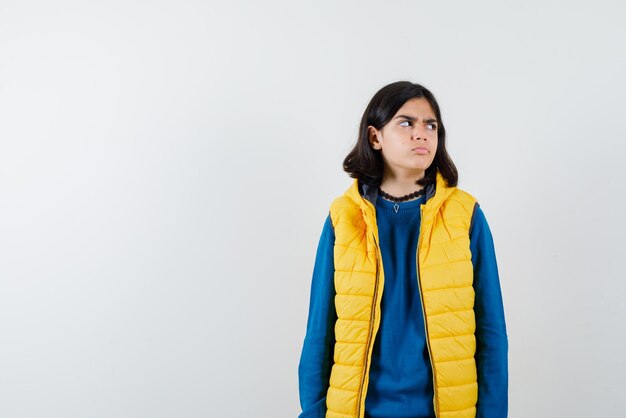 Teenage girl with a perplexed look on her face looking at something on the right on white background