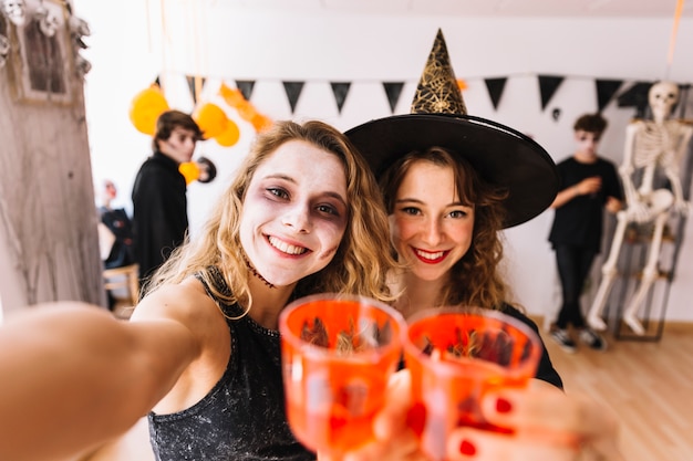 Teenage girls in Halloween costumes at party doing selfie