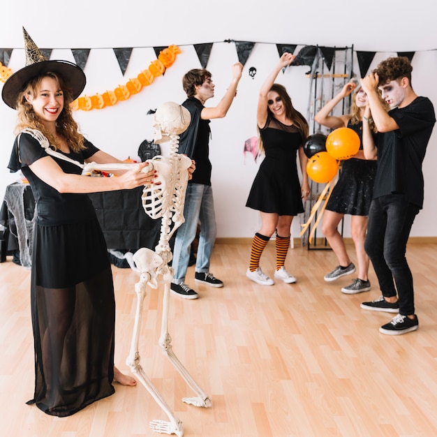 Teenage Halloween party with witch dancing with skeleton