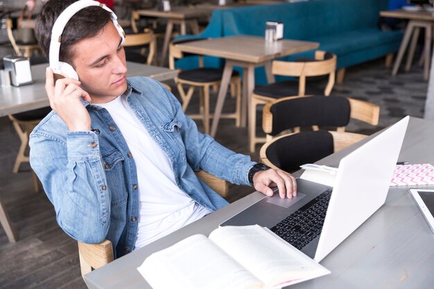 Teenage student in headphones sitting with notebook at table 