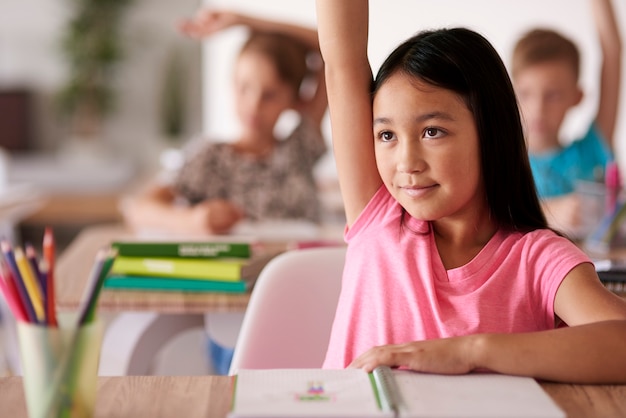 Teenage student raising hand in classroom