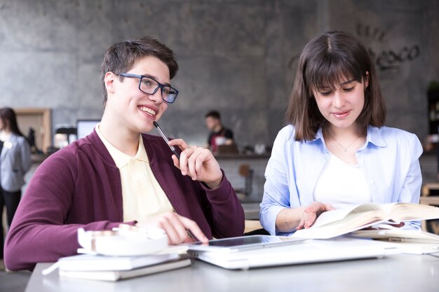 Teenage students sitting at table and studying 