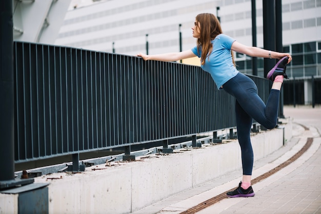 Teenageg leaning on fence and stretching leg