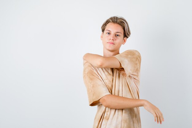 Teenager boy stretching arms in t-shirt and looking confident. front view.