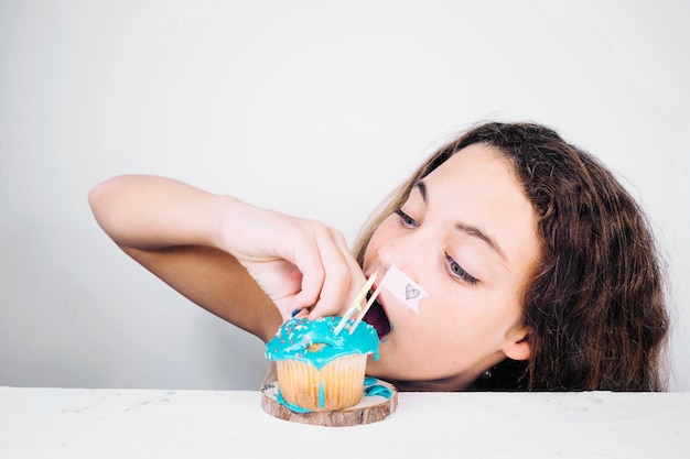 Foto gratuita adolescente che schiaccia cupcake prima di mangiarlo
