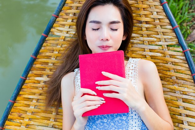 Teenager female lying on bamboo hammock and read a book