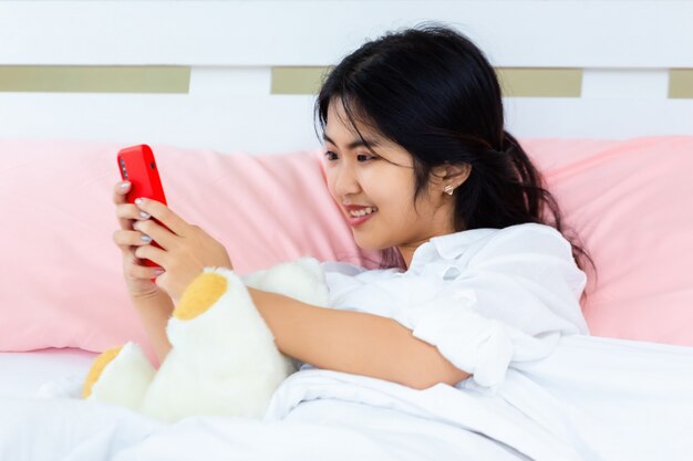 10代の女性がベッドでスマートフォンを使用します。