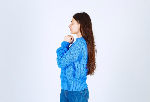 白の何かを考えている青いセーターのティーンエイジャーの女の子。