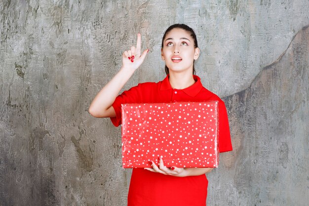 흰색 점이 있는 빨간색 선물 상자를 들고 거꾸로 보이는 10대 소녀