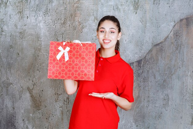 Teenager girl in red shirt holding a red shopping bag