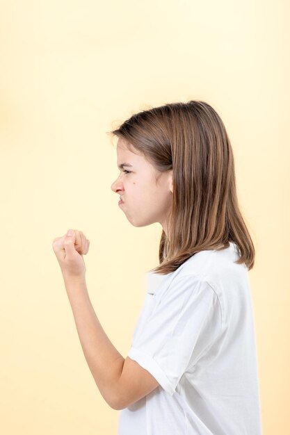 Free photo teenager girl shows fist on yellow background isolated side view