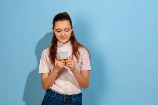 Teenager girl smiling, using smartphone
