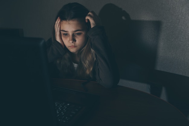 インターネット サイバー​いじめ​に​苦しんでいる 10 代​の​少女​は​、​ネット​いじめ​を​恐れ​、​落ち込んでいます​。​同級生​に​ネット上​で​嫌がらせ​された​絶望​少女​の​画像​。​ラップ​トップ​の​前​で​泣いている​若い 10 代​の​少女