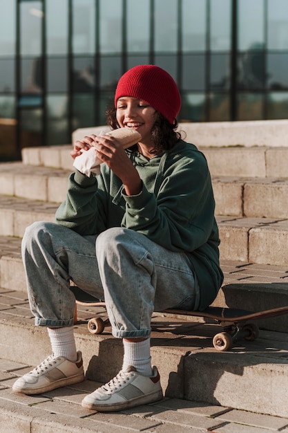 Teenager having lunch at the park on skateboard