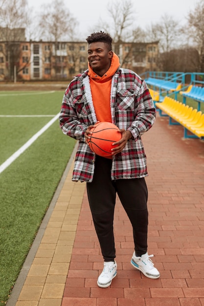 Foto gratuita adolescente che tiene la palla da basket all'aperto