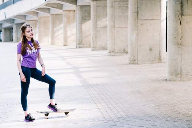 ティーンエイジャーは彼女の足を彼女のスケートボードに着地させる
