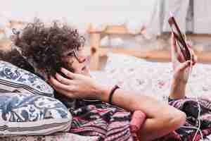 Free photo teenager listening to music and browsing smartphone on bed