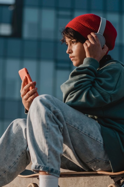 Подросток слушает музыку в наушниках во время использования смартфона