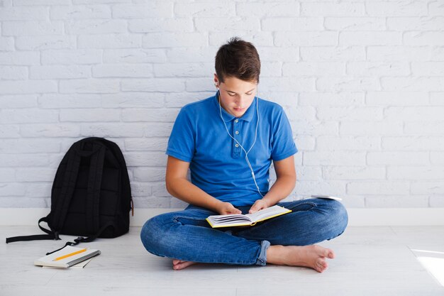 Teenager listening to music and reading book