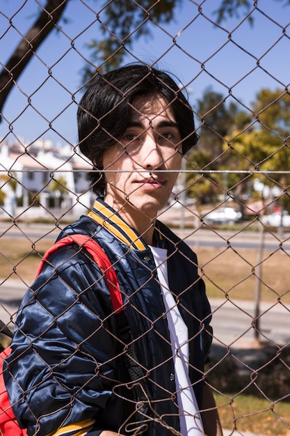 Teenager looking through fence in city