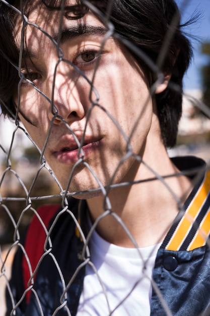 Teenager looking through fence in street