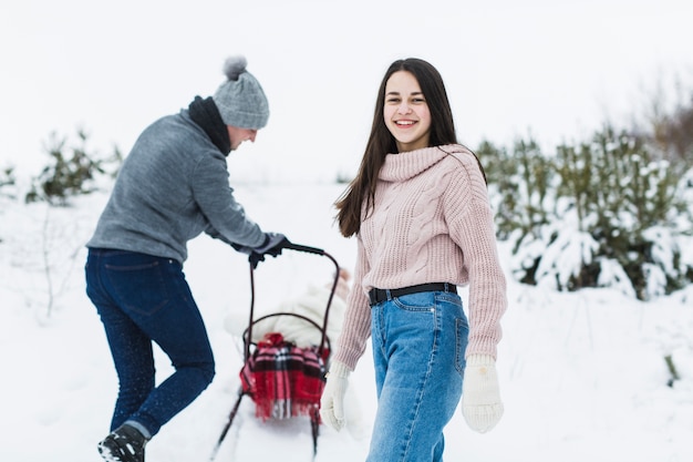 Teenager near father pushing sleigh