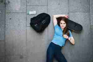 Free photo teenager posing with head on skateboard