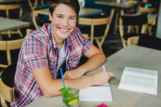 Teenager posing with notepad at table