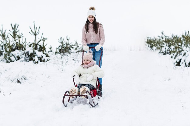 Free photo teenager pushing sleigh with sister