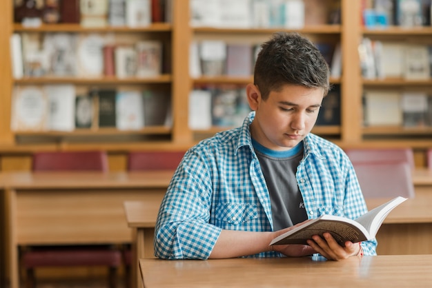 Подросток читает книгу в библиотеке