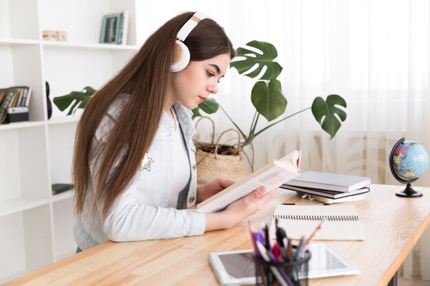 Teenager reading book with headphones on