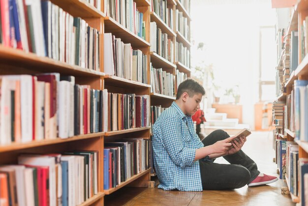 Teenager reading between bookshelves