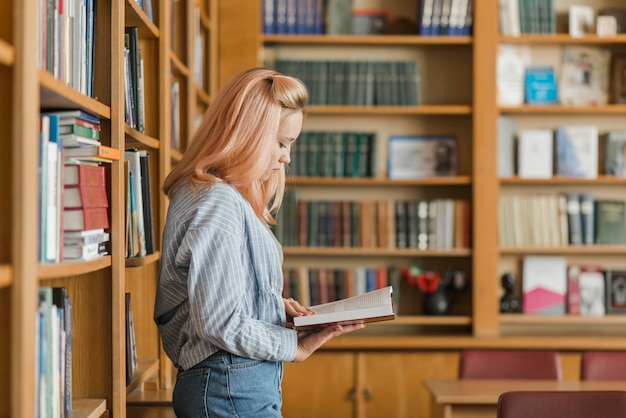 Teenager reading near bookshelves