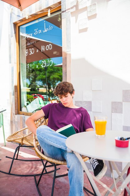 Teenager reading in outdoor cafe