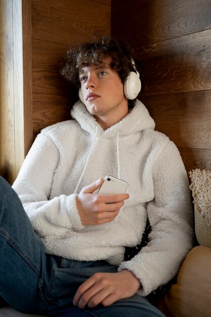 teenager sitting in his bed and listening music using his smartphone