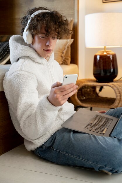 Teenager sitting in his bed and watching a video using his smartphone